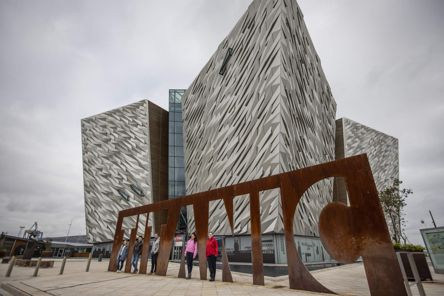 Titanic Quarter waterfront in Belfast featuring modern buildings, cranes, and clear blue skies along the harbor