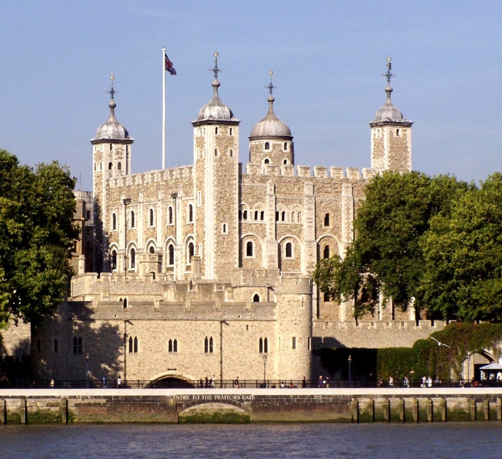 Tower of London historic stone fortress on the River Thames, iconic medieval castle with battlements and turrets under a cloudy London sky, popular tourist attraction and UNESCO World Heritage Site.