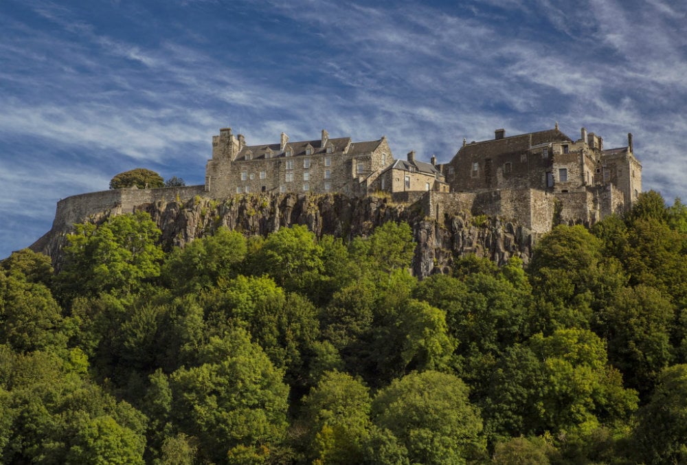 Stirling Castle viewed from the town of Stirling, Scotland, with historic stone buildings in the foreground and the hilltop fortress rising above.