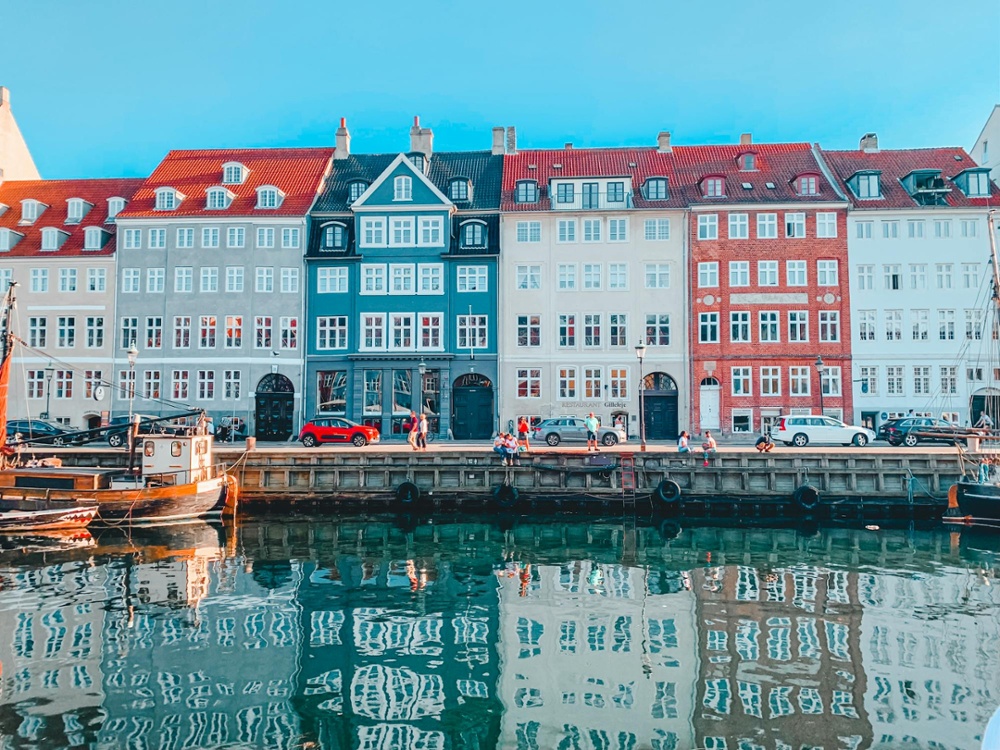 Colorful historic waterfront buildings reflected in the canal at Nyhavn in Copenhagen, Denmark on a bright sunny day.