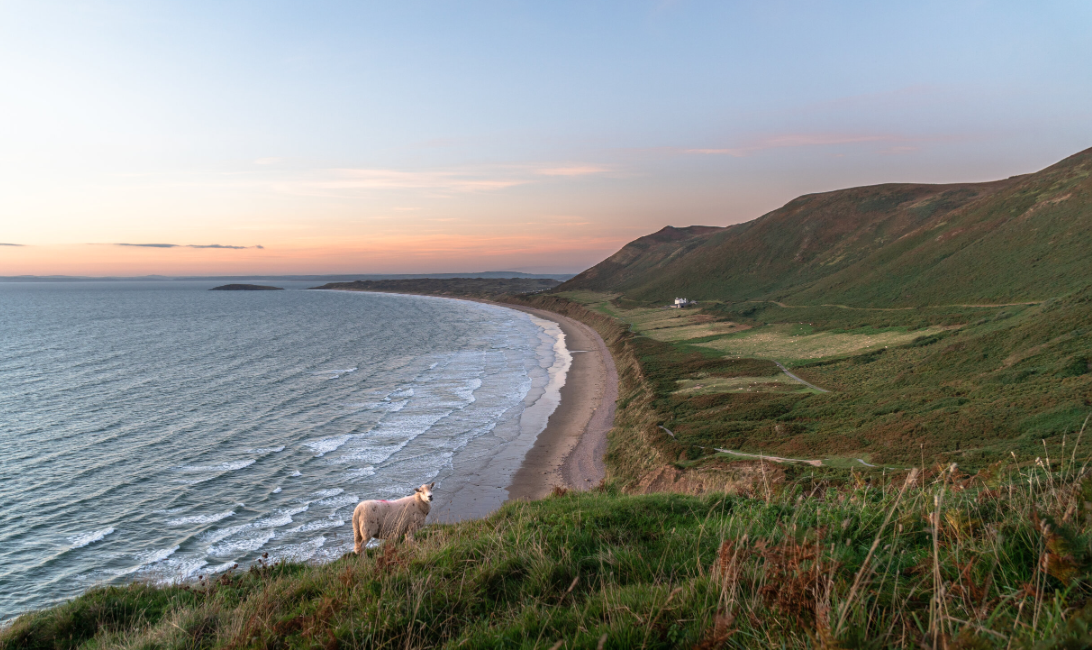 Dramatic Wales seascape with rugged cliffs, ocean waves, and a cloudy coastal sky